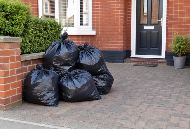 Tied black rubbish bags stacked on a driveway ready for collection